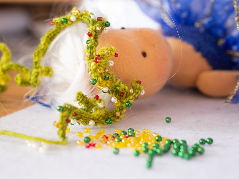 Glasperlen werden auf den gehäkelten Kopfkranz für Lucia gestickt, sie wartet geduldig und schon sehr gespannt auf diesen schönen Kopfschmuck anlässlich der Wintersonnenwende
