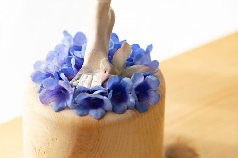 Rattenfuß aus Zehenspitzen im Glockenblumenblütenmeer auf Holzständer