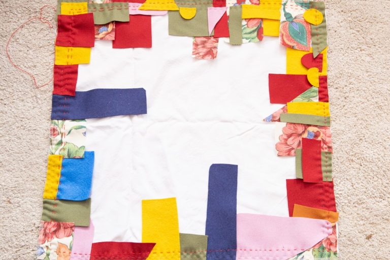 angefangener Kwandi Quilt, weiße Basisfläche, zwei bunte Reihen rundherum, handgenäht mit Steppstichen