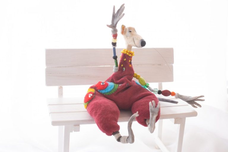 genähte Ratte mit aufgestickten kräftigfarbenen Kreisen, purpurner Hosenanzug, Perlenarme und gestreifte Wadeln