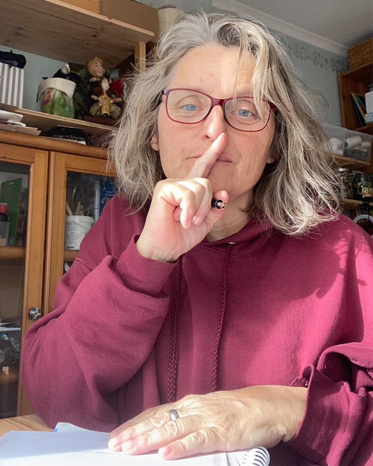 Frau mit magentafarbenem Pullover, hält einen Füller und denkt nach