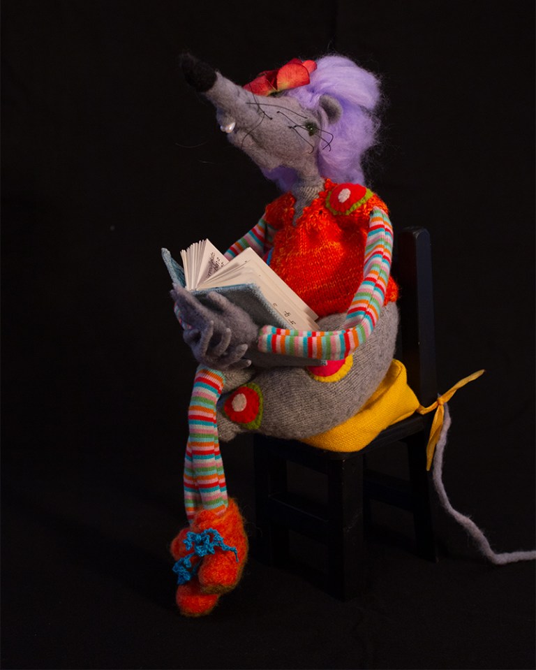 graue nadelgefilzte Ratte mit orangem Jackerl auf schwarzem Stuhl