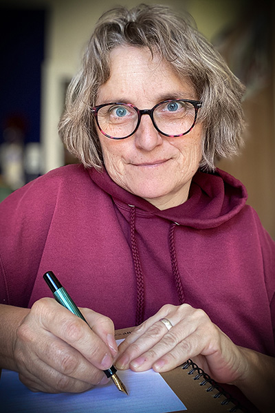 Lisa Engel schreibt mit einer Füllfeder auf einem weißen Blatt Papier